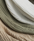 Närbild av muslinfiltarna i beige Sand, gröna Sage och vita Ivory