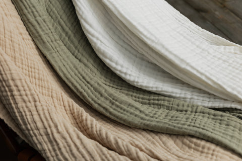Närbild av muslinfiltarna i beige Sand, gröna Sage och vita Ivory