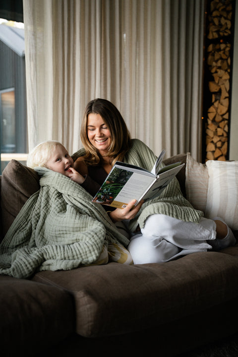 En kvinna i soffan med den gröna muslinfilten Stora Sage